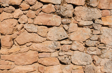 Wall of old stone rural house of large size with a lot of texture and warm tones.