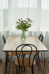Bouquet of fresh pink peonies in transparent jar standing on the table indoors