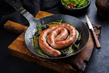 Traditional fried Italian salsiccia fresco meat sausage served with rocket salad and olives in a...