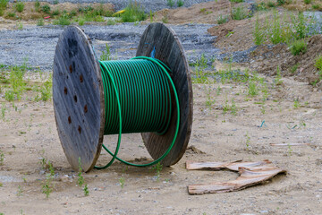 A wooden reel with the remains of a green cable on a construction site.