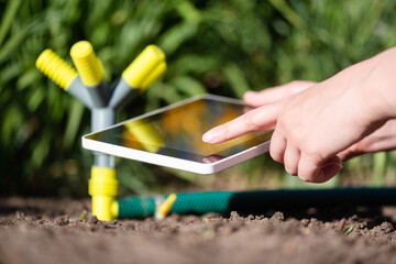 A gardener with a digital tablet using a smart garden application concept. Watering system....
