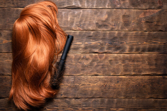 Hairdressing salon concept background. Redhead women wig and combs on the hairdresser table flat lay background with copy space.