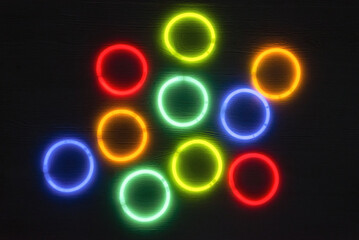 Colorful neon lighting bracelets on the dark black background.