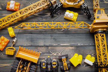 Yellow construction crane, bulldozer toy and control joypad on the wooden flat lay table background. © Natali