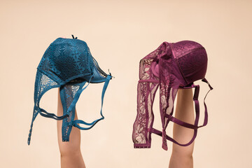 Woman a customer is choosing a new bra in a lingerie store. Woman holds in hand a various bra above...