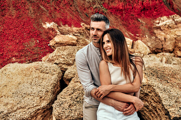 Vacation romantic love middle aged happy couple hug and standing at sand rock having fun and relaxing together on the beach.