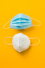 medical protective face masks on vertical yellow background, coronavirus prevention 