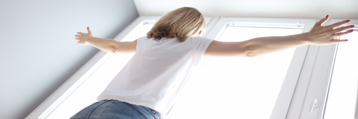 Woman standing at the window with her arms wide open