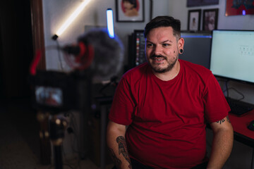 Chico joven gordo con camiseta roja grabando frente a una cámara en un set up gamer