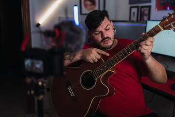 Fototapeta na wymiar Chico joven gordo con camiseta roja grabando frente a una cámara en un set up gamer