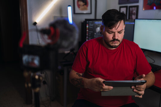 Chico joven gordo con camiseta roja grabando frente a una c&aacute;mara en un set up gamer
