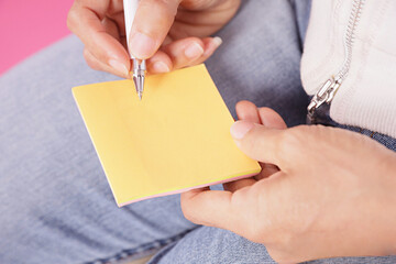 woman writing message on yellow note paper.