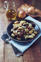 Gnocchi with onion and mushrooms. Rustic wooden background. 