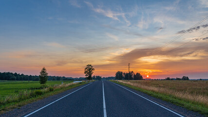 Summer sunset in the countryside. The road to the west.