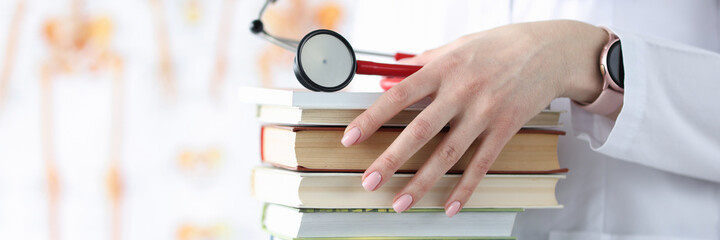 Doctor hands are holding stack of books and stethoscope