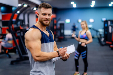 Young attractive sporty male instructor. Handsome personal trainer working with his client.