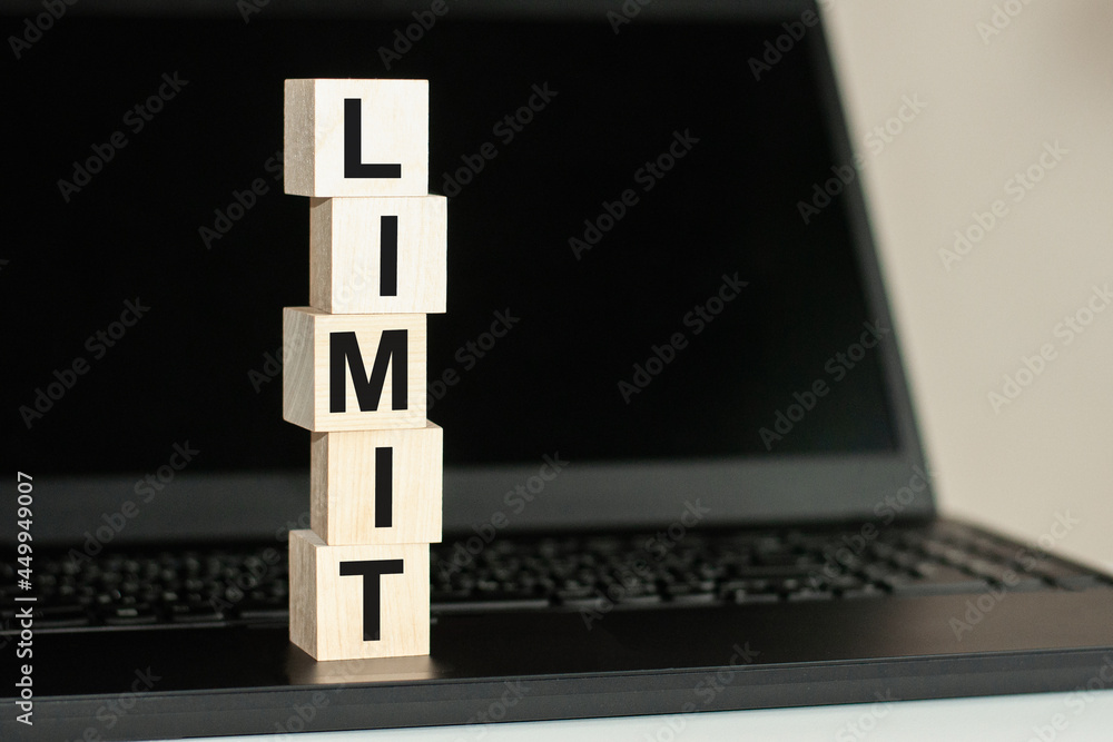 Poster limit word made with building blocks on the black keyboard. a row of wooden cubes with a word writte