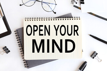 Open your Mind. text on notepad. on a white background near the stationery