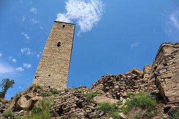 tall stone battle tower of old Kahib - abandoned ancient village in Dagestan caucasus mountains with blue summer sky background