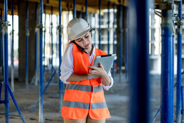 Female construction engineer. Architect with a tablet computer at a construction site. Young Woman looking, building site place on background. Construction concept