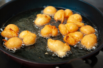 Delicious and traditional Brazilian homemade sweet called BOLINHO DE CHUVA being fried in a frying pan.