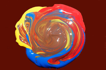 mixed red, blue and yellow colors of acrylic paint on a brown background . mix the base colors to get a brown color
