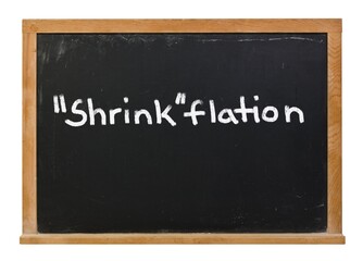 Obraz premium Shrinkflation written in white chalk on a black chalkboard isolated on white