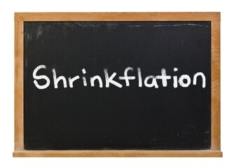 Shrinkflation written in white chalk on a black chalkboard isolated on white