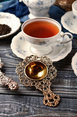 Antique silver tea strainer in the composition on the table.