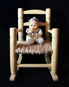 Peque&ntilde;a mu&ntilde;eca de trapo en una silla mecedora para ni&ntilde;os