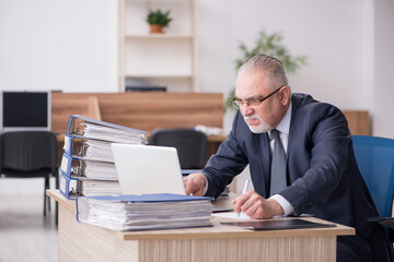 Aged male employee sitting at workplace