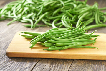 green bean pods on a cutting board, rustic style.