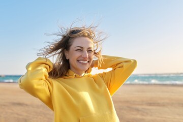 Outdoor portrait of smiling happy blonde woman 45 years old looking at camera