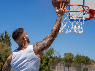Hombre joven con tatuajes  jugando a baloncesto  © David Martínez