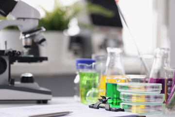 Microscope multicolored liquid in test tubes and papers on table in laboratory