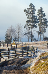 Winter coming. Last days of autumn, morning in mountain countryside peaceful picturesque hoarfrosted scene. Dirty road from hills to the village. Ukraine, Carpathian mountains.