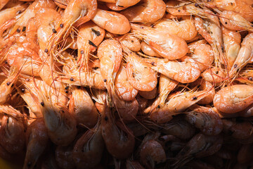 Boiled shrimp unpeeled in a yellow bowl bowl on a gray-brown wooden surface, light shadow, sunlight. Lots of shrimp in a bowl. Shrimp close-up. Top view with space for text. Banner