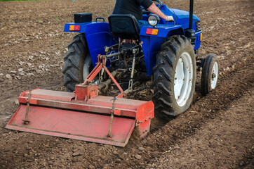 The tractor is cultivating the soil in the farm field. Freeing milling earth ground from old crops....