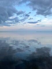 evening clouds reflecting onto still bay water
