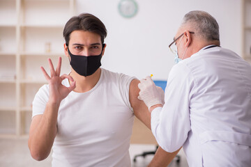 Young male patient visiting old doctor in vaccination concept