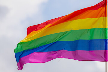 Rainbow flag hanging on top of the building and waving on the air with blue sky background, The symbol of gay, lesbian, bisexual and transgender, Social movements around the world, LGBTQ community.