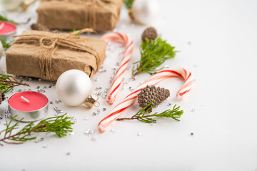 Original Christmas and New Year composition on a white background. Coniferous branches, candy canes, Christmas decorations, pine cones, gifts, scattered silver confetti. Christmas, New Year.