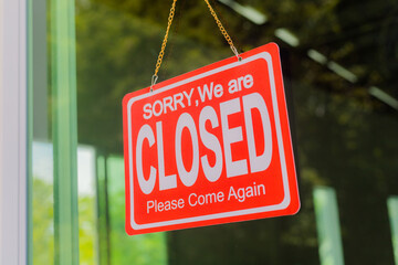 Fototapeta premium The shop owner hangs a sign to close the business in front of the door.