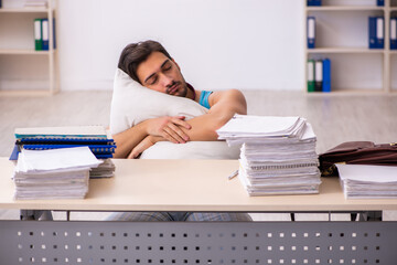 Young male employee coming to work straight from bed