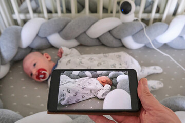 Monitoring of a newborn baby in a crib through a home security camera online and the Internet in a...