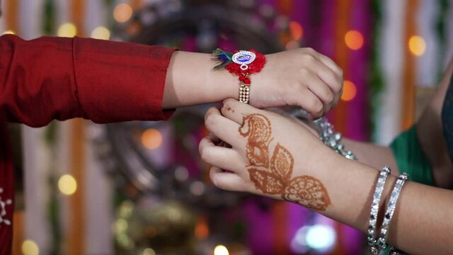 Sister tying the rakhi, Raksha Bandhan to brother's wrist during festival or ceremony - Raksha Bandhan celebrated across India as selfless love or relationship between brother and sister.