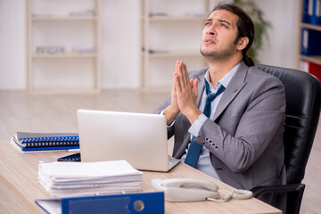 Young male employee unhappy with excessive work in the office