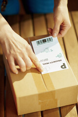 Modern woman in office applying shipping label to parcel