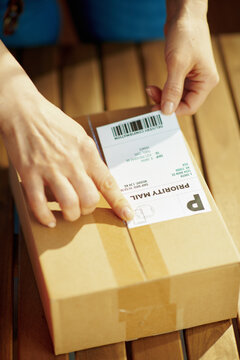 Modern woman in office applying shipping label to parcel