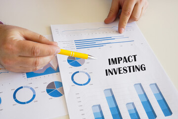 Banker present to the phrase IMPACT INVESTING on the printout with diagrams and tables.